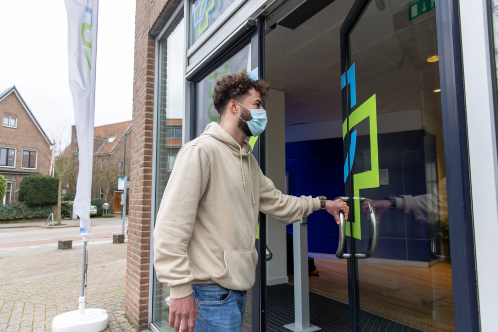 Jongen met mondkapje gaat coronatestlocatie binnen voor een PCR-test in Amsterdam