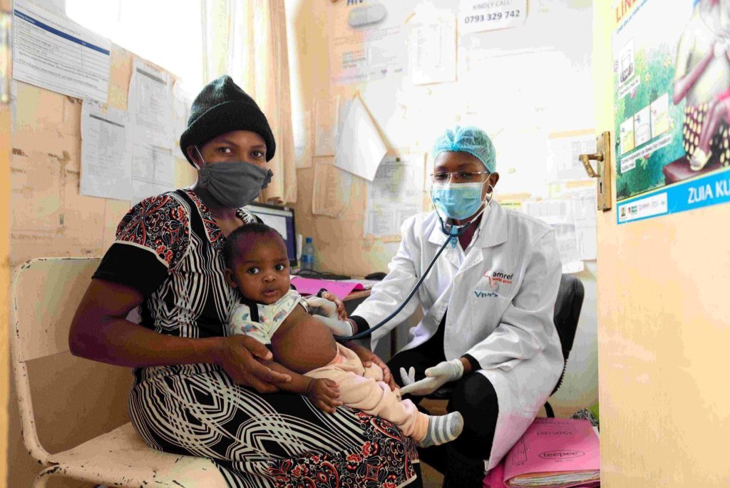 Afrikaanse vrouw met haar kind bij een zorgverlener van Amref Flying Doctors.